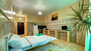 Un dormitorio con una cama, una alfombra verde, un escritorio y un televisor.
