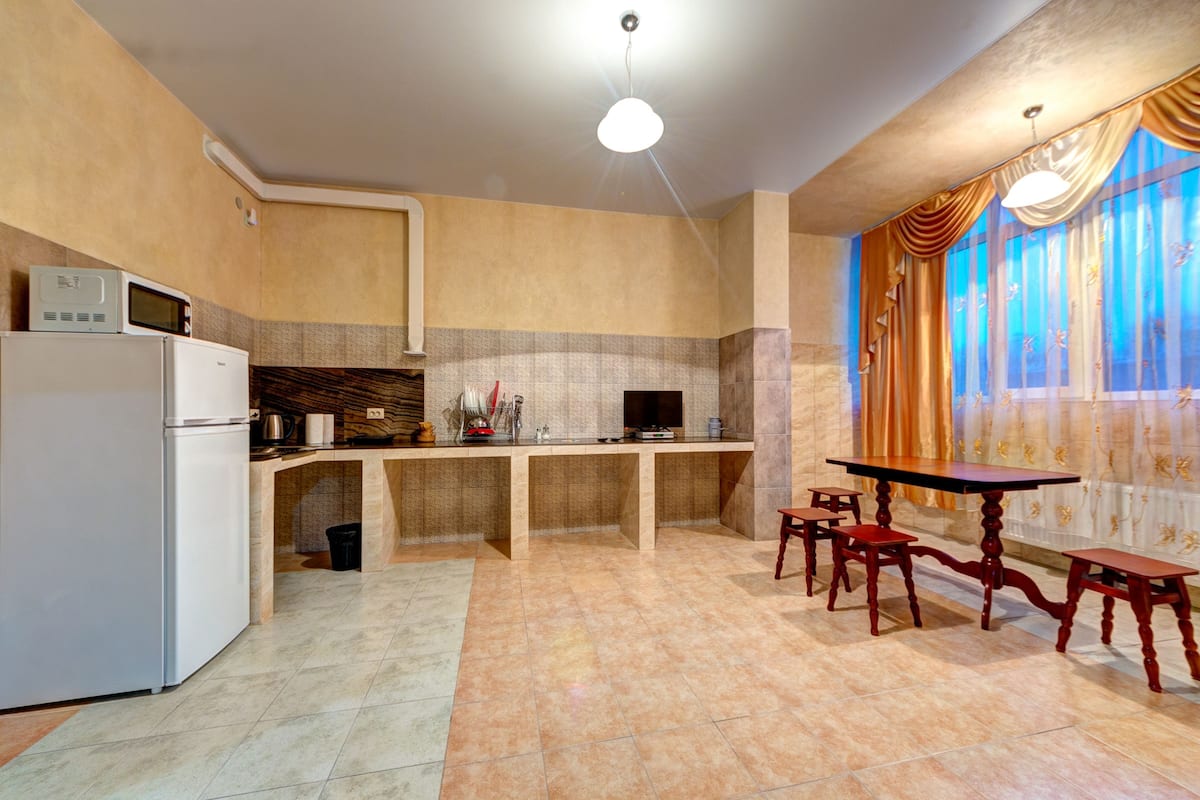 A modern kitchen with a refrigerator, microwave, and sink. There is a dining area with a table and chairs.