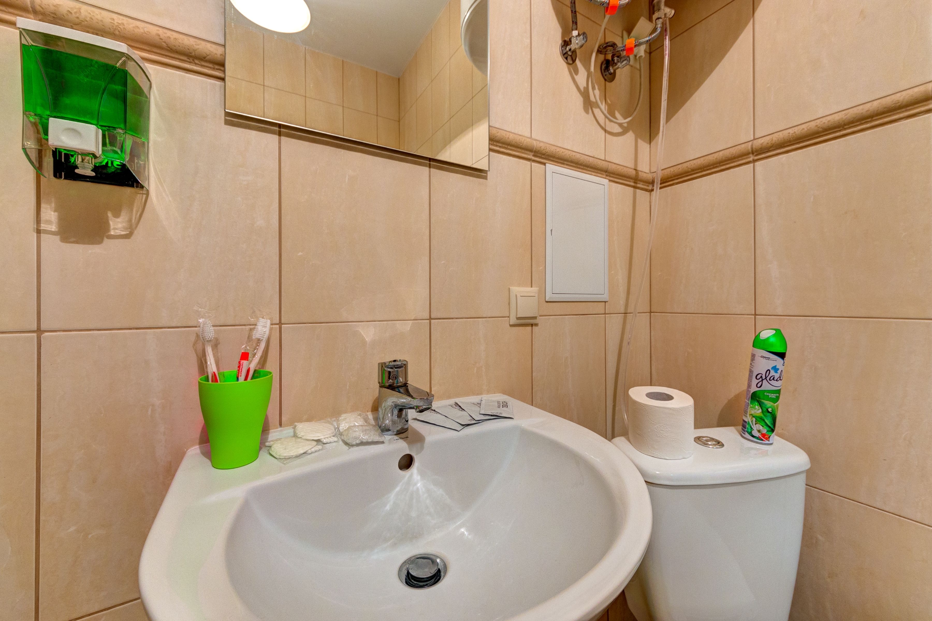 Ein Badezimmer mit Waschbecken, Toilette und einer grünen Tasse mit Zahnbürsten.