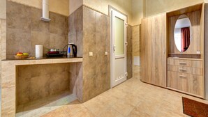 Un baño moderno con baldosas color beige, una puerta blanca y un mueble de tocador de madera con espejo.