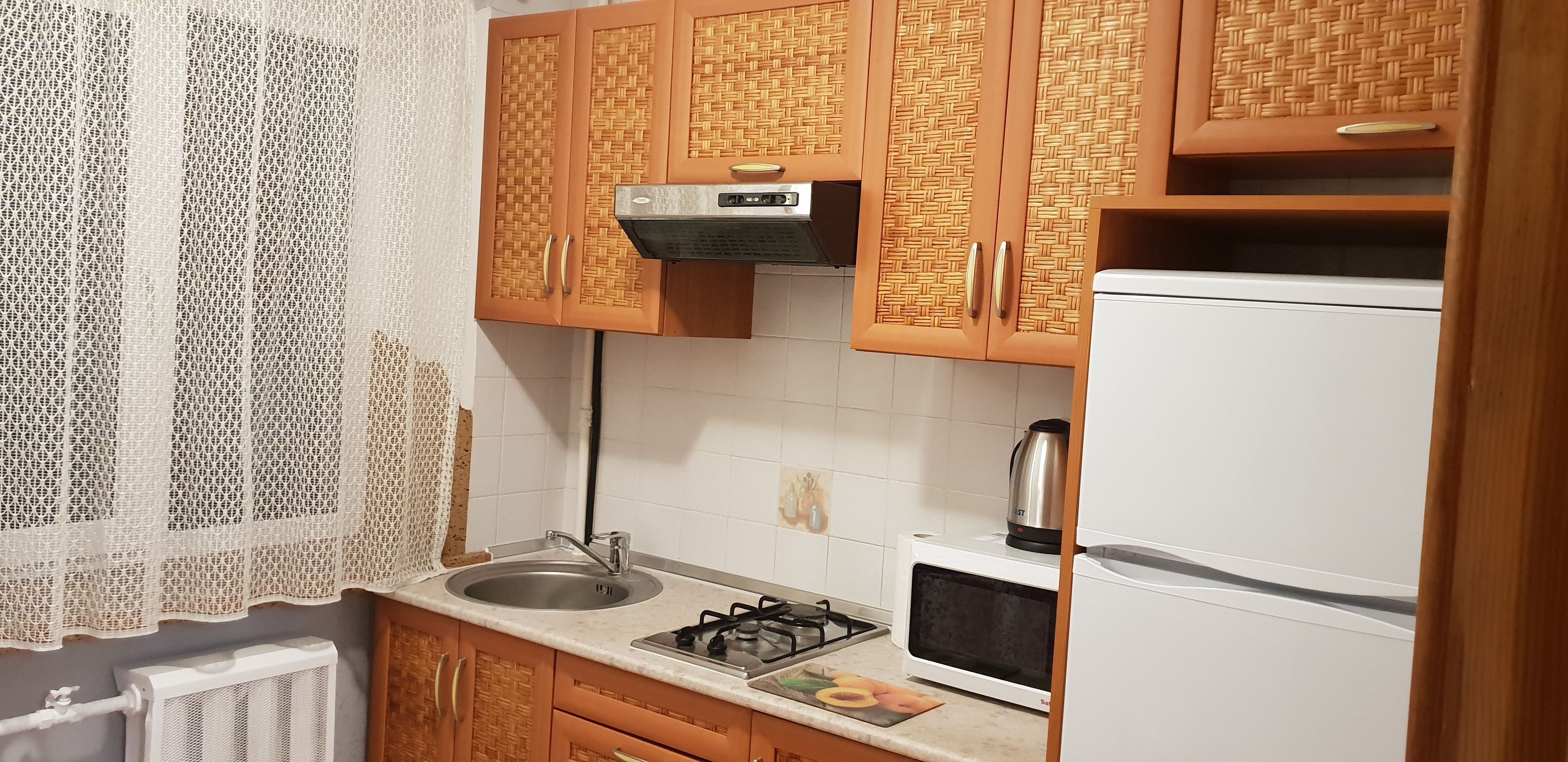 Une cuisine dotée de meubles en bois, d’un évier en acier inoxydable, d’une cuisinière à gaz, d’un four à micro-ondes et d’un réfrigérateur.