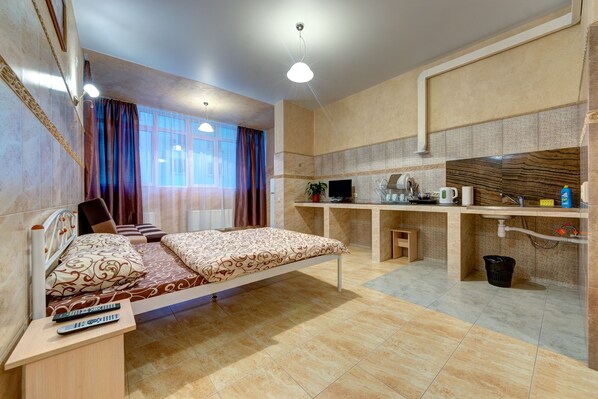 A compact hotel room with a bed, a desk, a TV, and a small bathroom area.