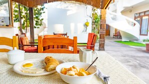 Una mesa de desayuno con cruasanes, un bol de fruta y una cafetera.