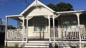 A white two-story house with a porch, large windows, and a triangular roof. - Modern Home in Convenient Location (Auckland)