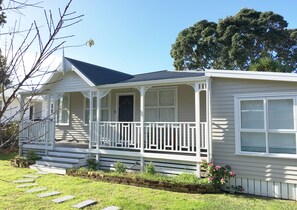 A single-story house with a porch, a front door, and a small front yard with a brick pathway. - Modern Home in Convenient Location (Auckland)