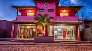 Un edificio de dos pisos con una fachada rosa vibrante, amplias ventanas de vidrio y un techo de tejas.