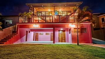 A modern two-story house with a balcony, a staircase, and a well-lit entrance.