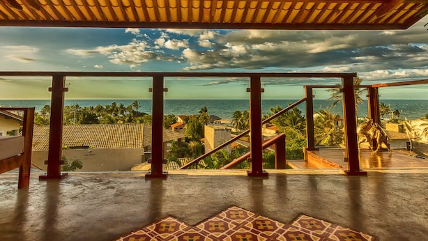 Un balcón con vista al mar y palmeras.