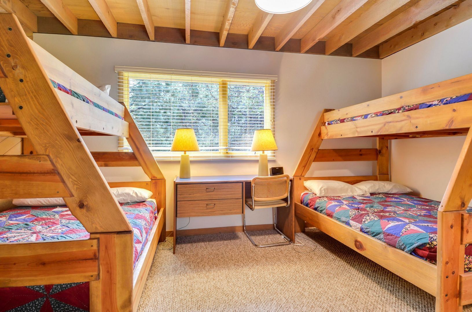 Ein Schlafsaalzimmer mit Etagenbetten, einem Schreibtisch und einem Stuhl.