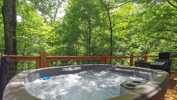 A hot tub on a wooden deck surrounded by trees.