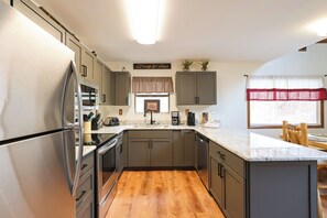 Uma cozinha moderna com eletrodomésticos de aço inoxidável, piso de madeira e uma janela com vista.