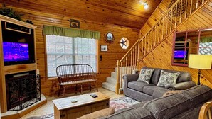 A cozy log cabin interior with a wooden staircase, a sofa, a bench, and a fireplace. - Secluded cabin, great location, hot tub, and foosball! (Sevierville)