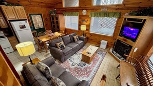 A cozy cabin interior with a dining area, sofa set, TV, and fireplace. - Secluded cabin, great location, hot tub, and foosball! (Sevierville)