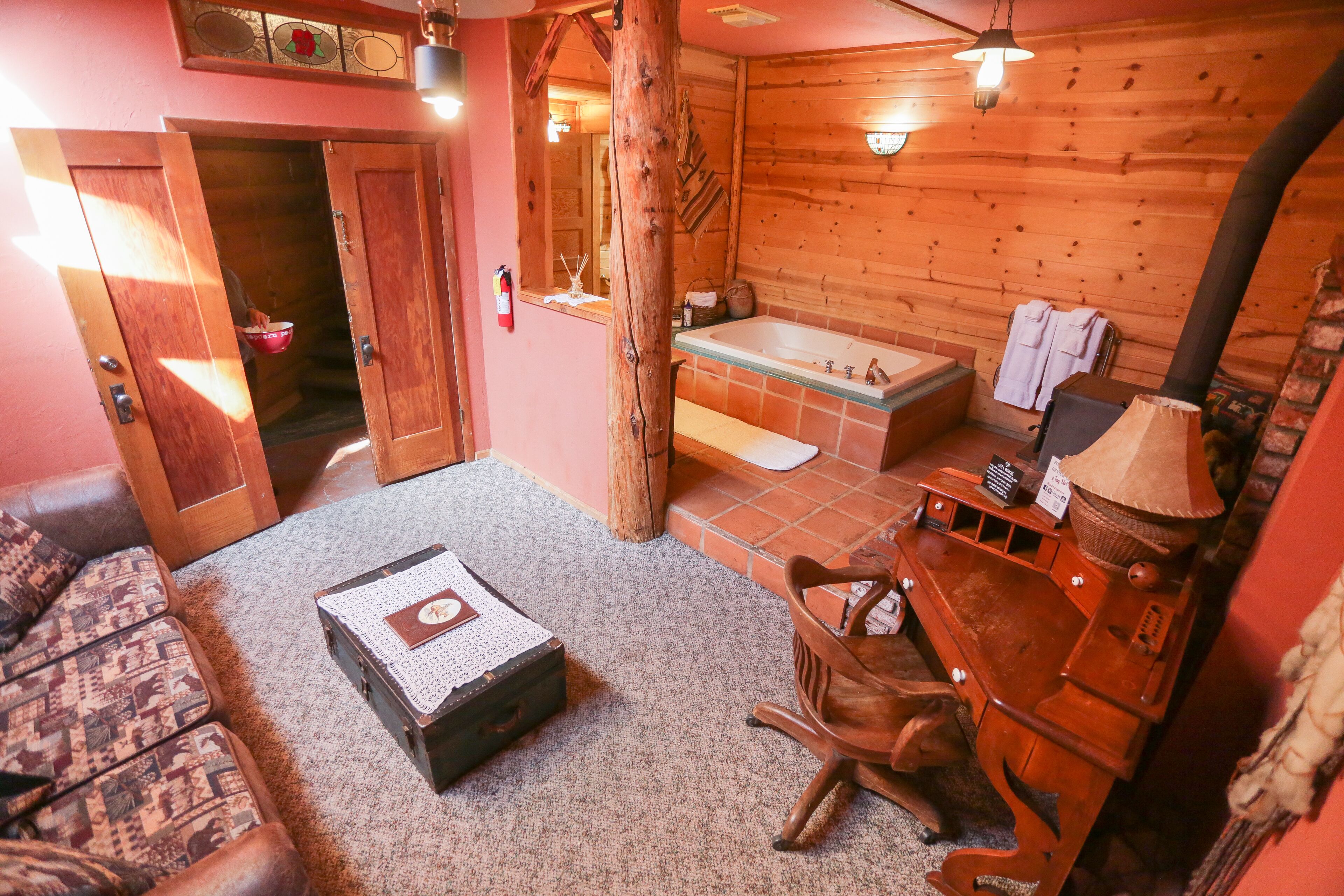 A wooden interior with a bathtub, a wooden chair, and a suitcase on the floor.