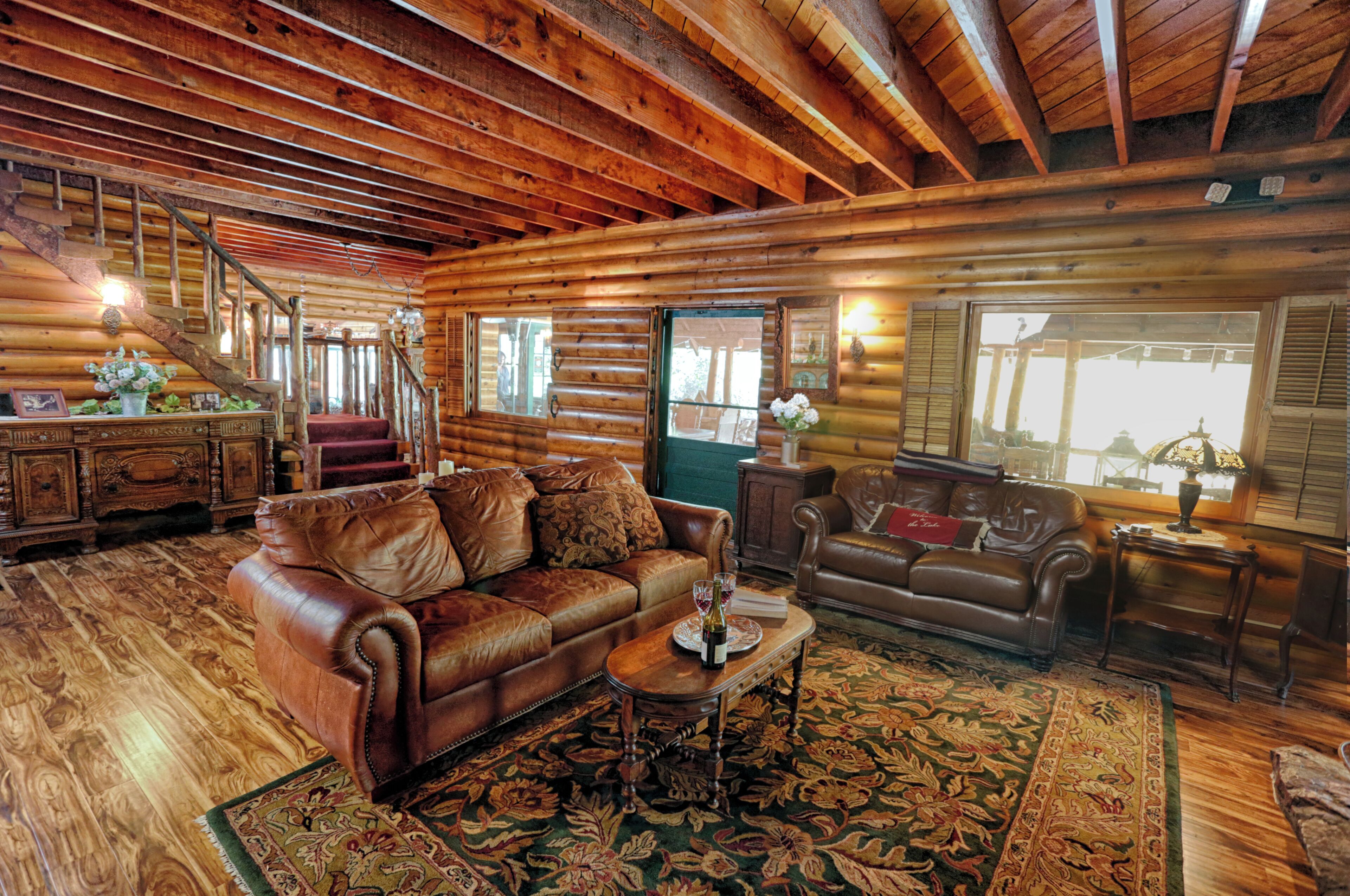 A log cabin interior with a leather sofa, a wooden coffee table, and a patterned rug.