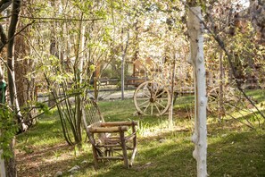 Un banc en bois rustique dans un jardin, avec une vieille roue de charrette en arrière-plan.