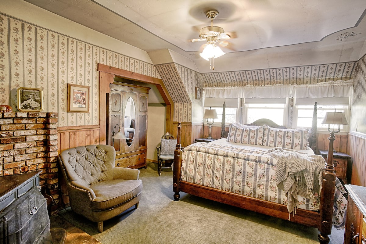 A bedroom with a wooden bed, a chair, a dresser, and a mirror.