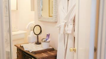 Une salle de bain avec un meuble-lavabo en bois, un miroir, une serviette et un peignoir accroché à la porte.