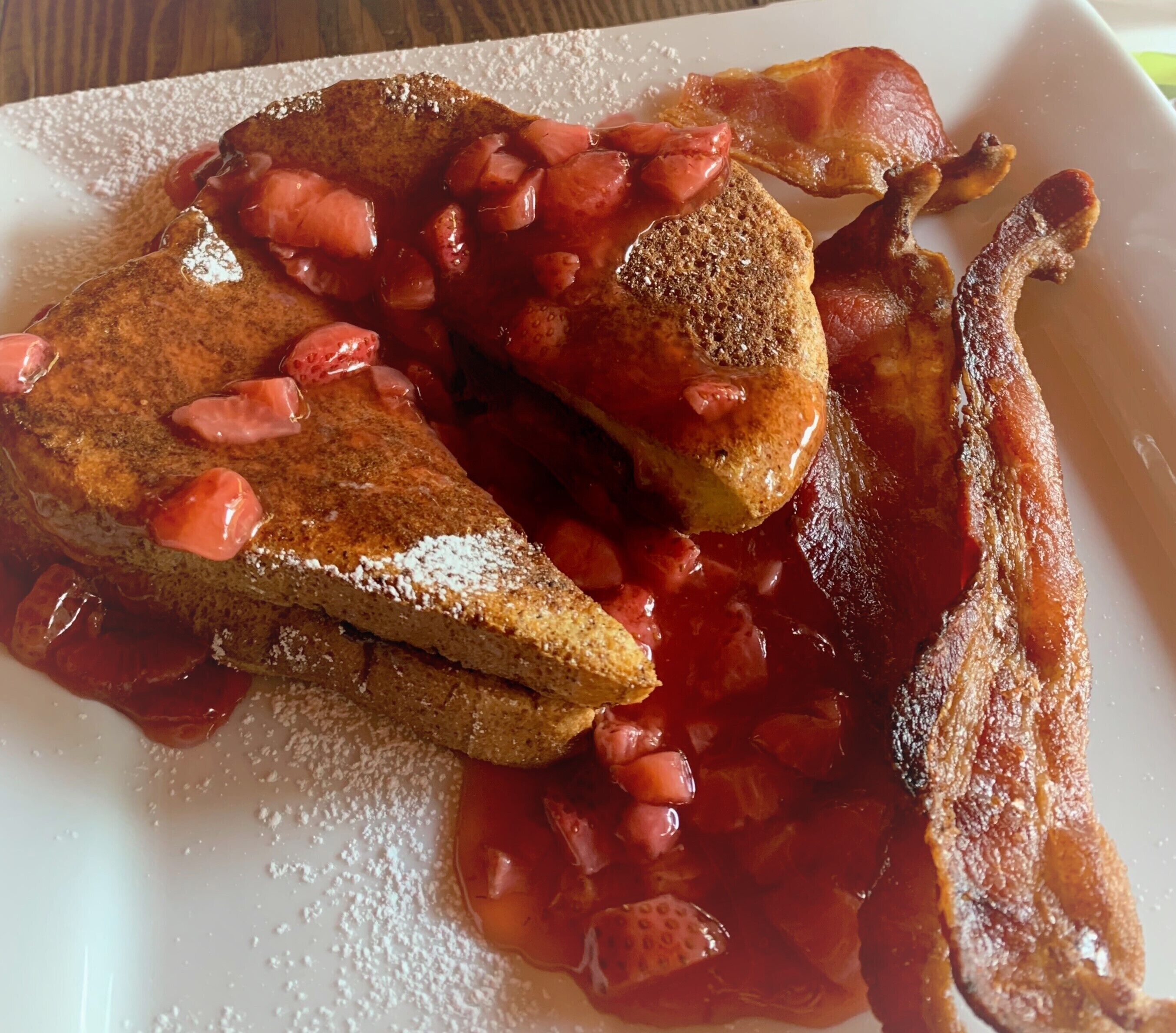 A plate with toast, bacon, and a red sauce.