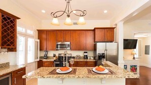 A modern kitchen with granite countertops, stainless steel appliances, wooden cabinets, and a central island with two plates of food.