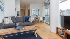 Un salon moderne avec un canapé gris, une table basse en bois et un meuble pour la télévision.
