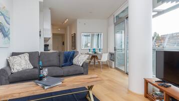 Una sala de estar moderna con un sofá gris, una mesa de centro de madera y un mueble para televisor.