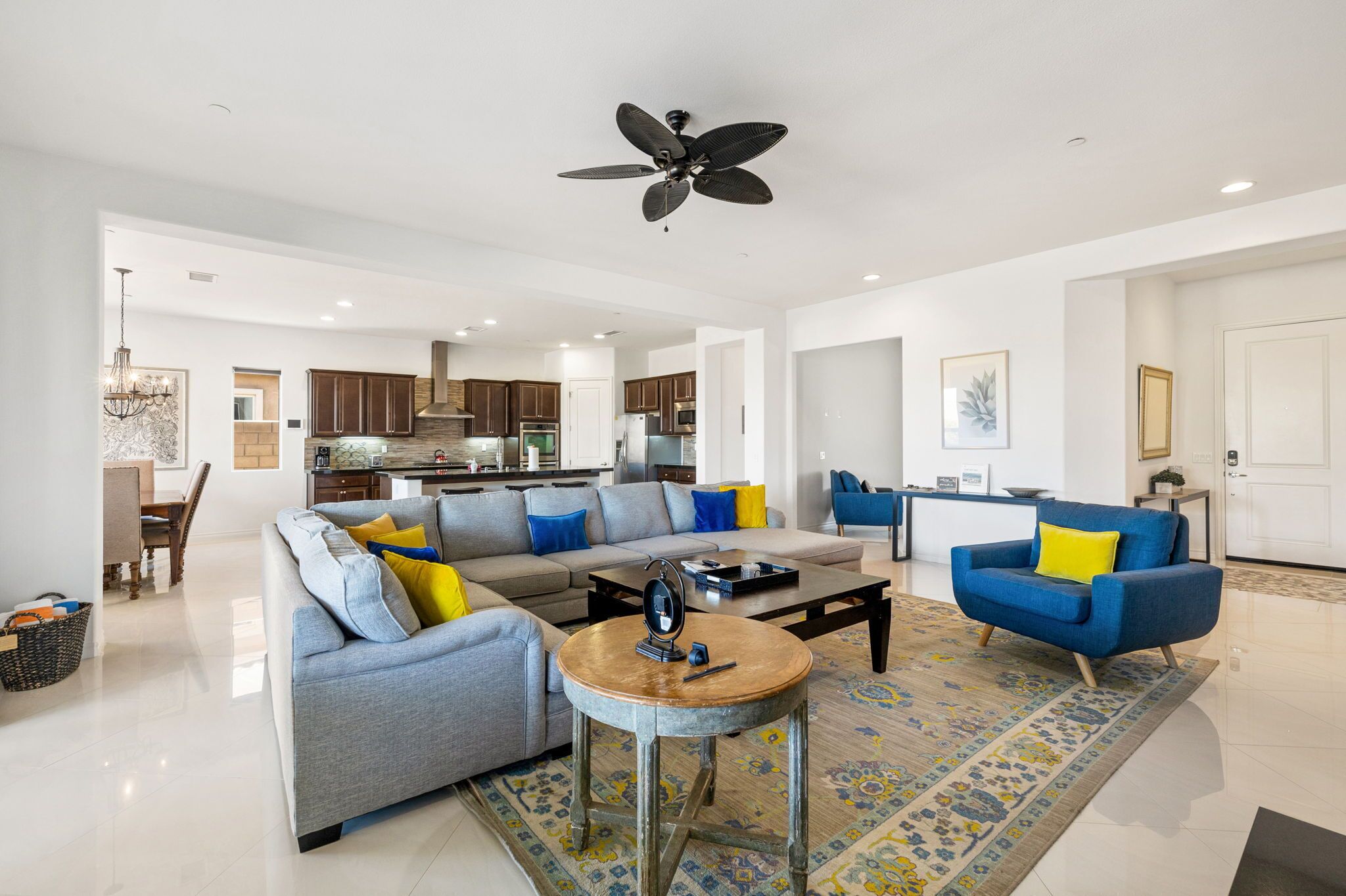 A spacious living room with a grey sofa, blue armchair, and a coffee table.