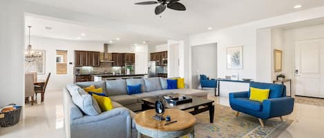A spacious living room with a grey sofa, blue armchair, and a coffee table.