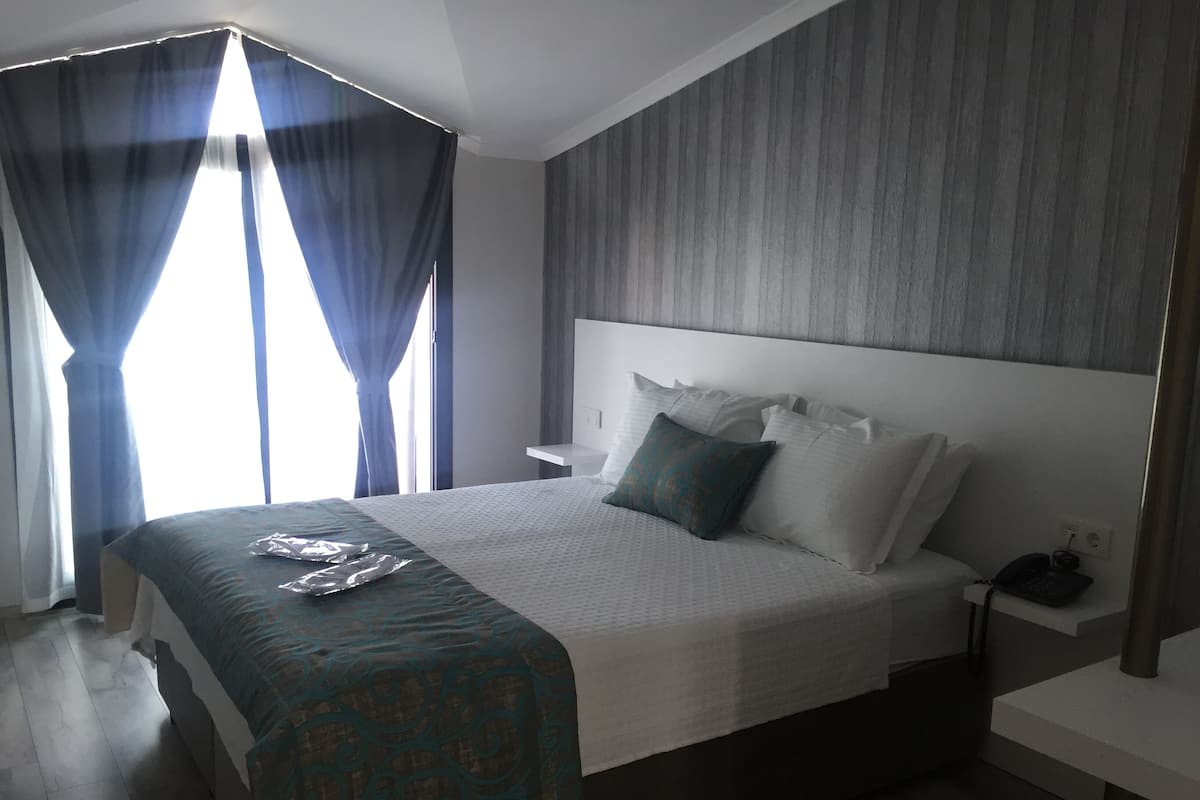 A modern hotel room with a large bed, a bedside table, and a nightstand.