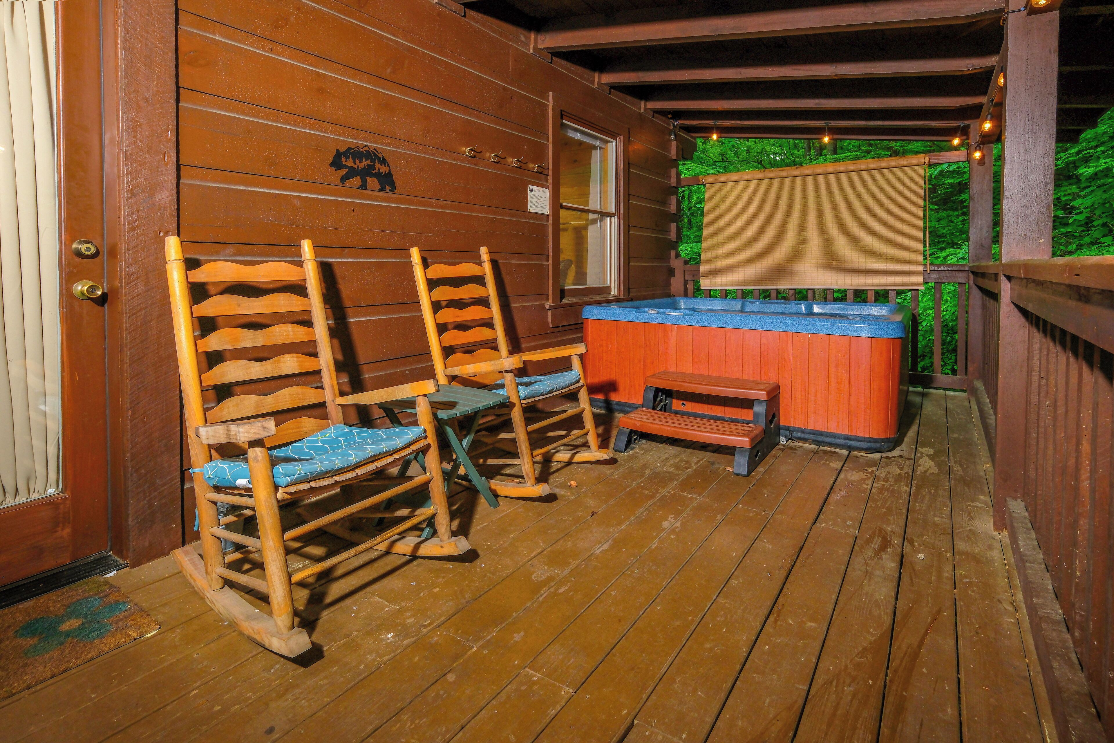 A wooden deck with rocking chairs and a hot tub.