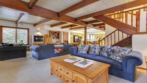 A spacious living room with a large blue sofa, a wooden coffee table, and a staircase leading to an upper level. - 2 Tokatee-Sunriver, Oregon: Hot Tub, BBQ, WiFi, SHARC Aquatics, Tubing Hill, Mt. Bachelor, Golf, Deschutes River, Tennis, Bike Paths (Sunriver)