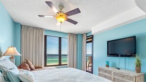 Ein Schlafzimmer mit Bett, Deckenventilator, Fernseher und Meerblick.