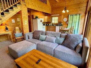 Relax in this inviting cabin with a comfortable sofa, wooden coffee table, and staircase leading to an upper level.