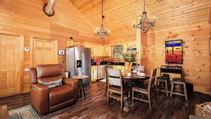 A wooden cabin interior with a dining area, a leather recliner, a chandelier, and a mounted deer head. - Outdoor TV on screened in porch, hot tub, arcade game, ticket to Dollywood (Sevierville)