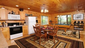Een houten chalet van binnen met een keuken, eethoek en pooltafel.