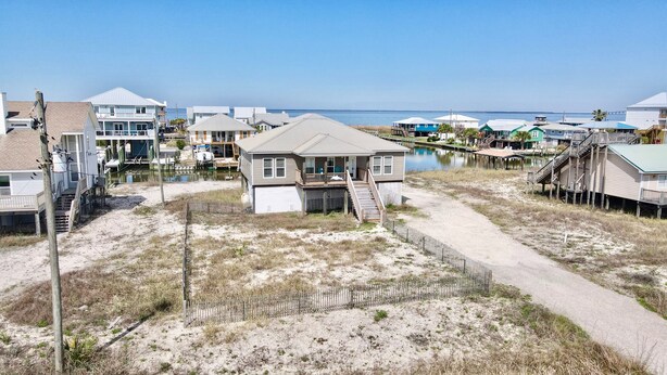 A beachfront house with a front deck, a small porch, and a pathway leading to the entrance.