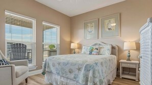 A bedroom with a bed, two bedside lamps, a chair, and a window with blinds.