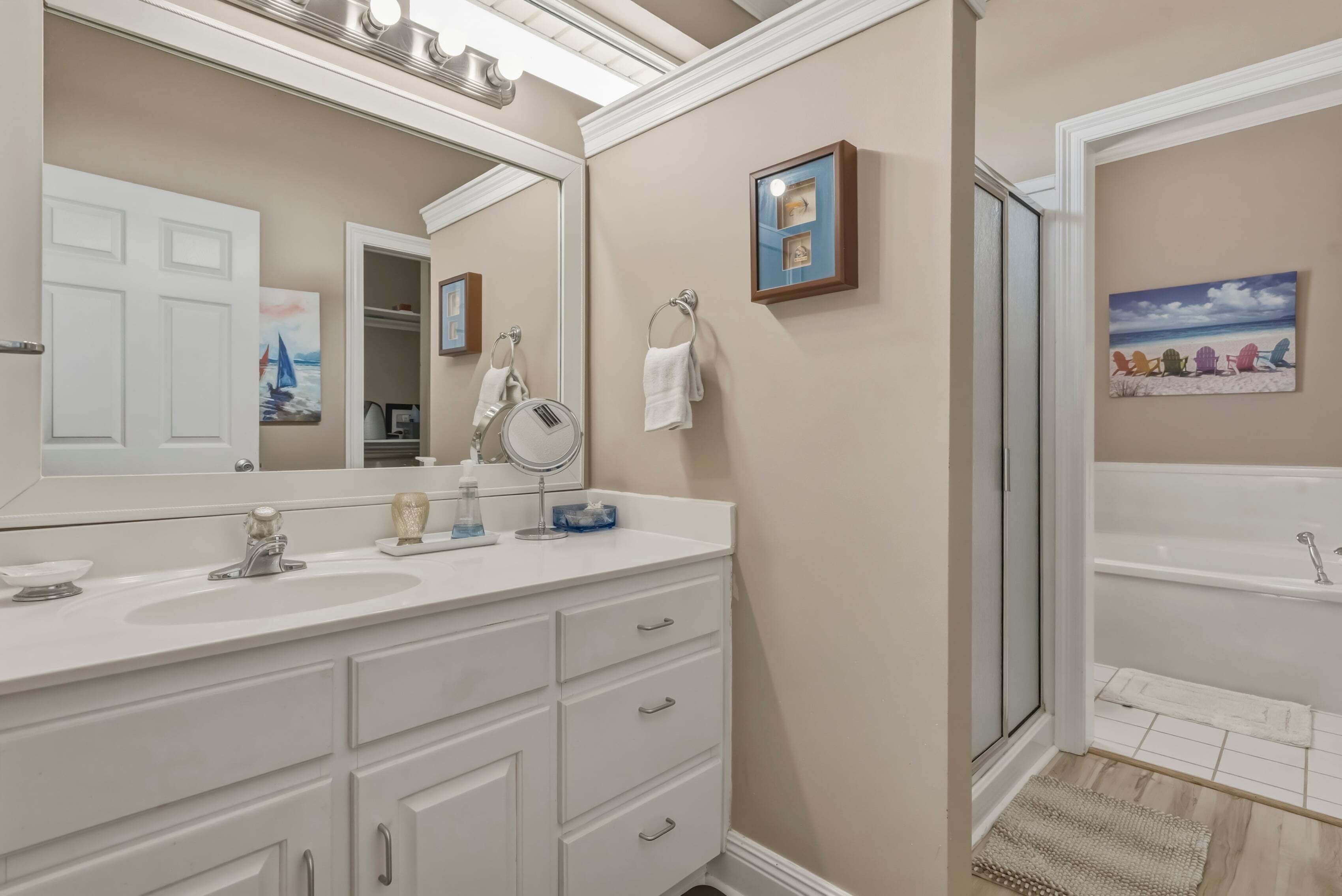 Une salle de bain avec un grand miroir, deux lavabos, un porte-serviettes et une baignoire.