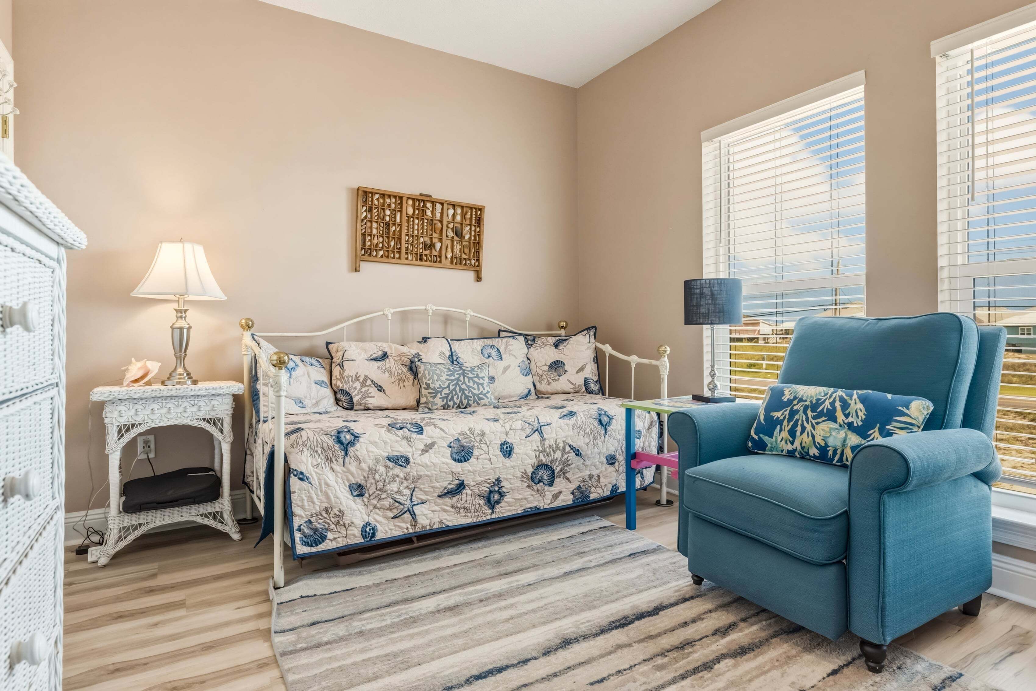A bedroom with a bed, a chair, a nightstand, a lamp, and a window with blinds.