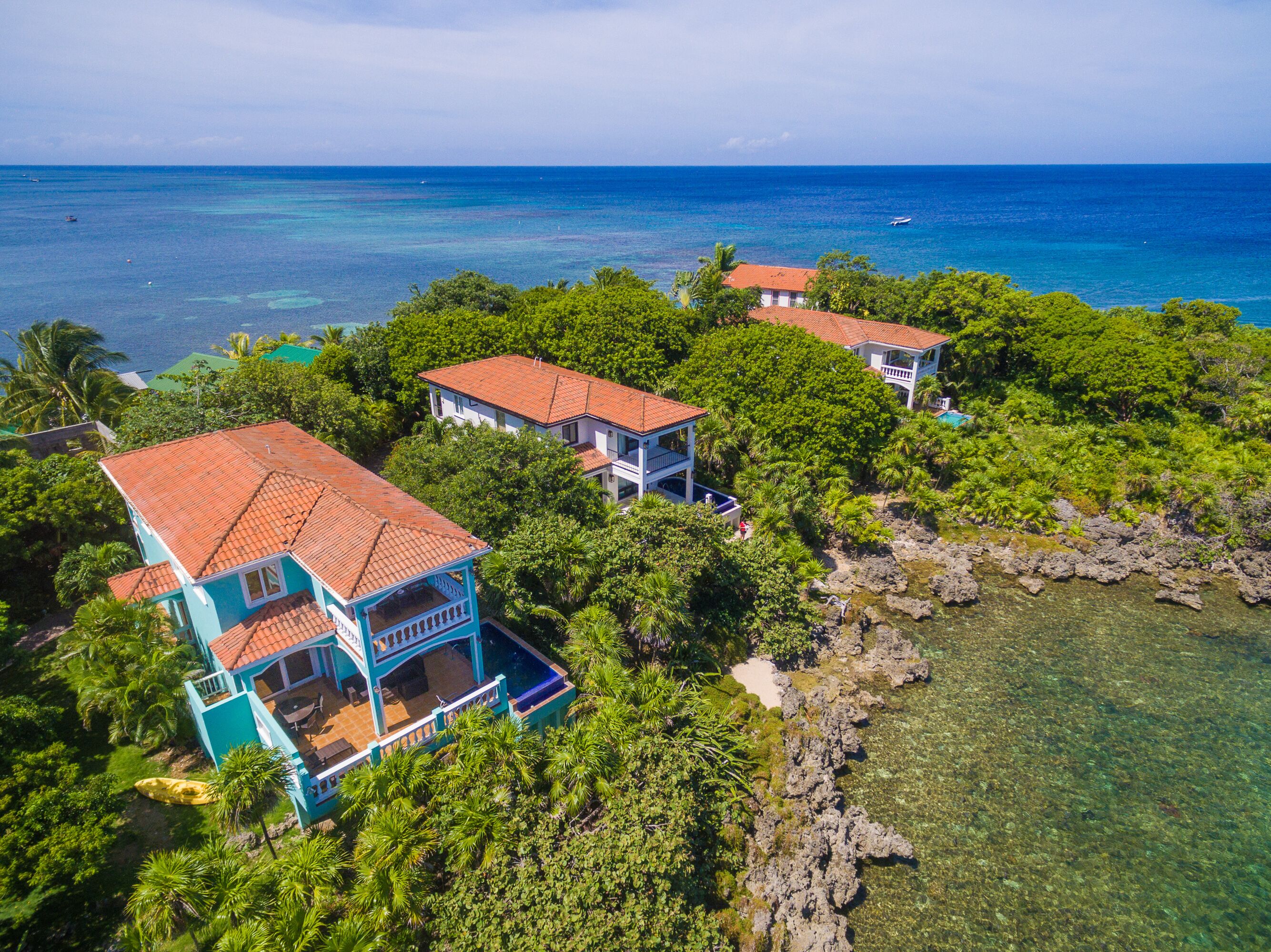 A coastal property with multiple buildings surrounded by lush greenery and clear blue waters.