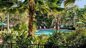 A pool surrounded by lush greenery and palm trees, with lounge chairs and umbrellas. - **OCTOPUS'S GARDEN @ CORAL HAMMOCK** Pool + Last Key White Glove Service... (Key West)