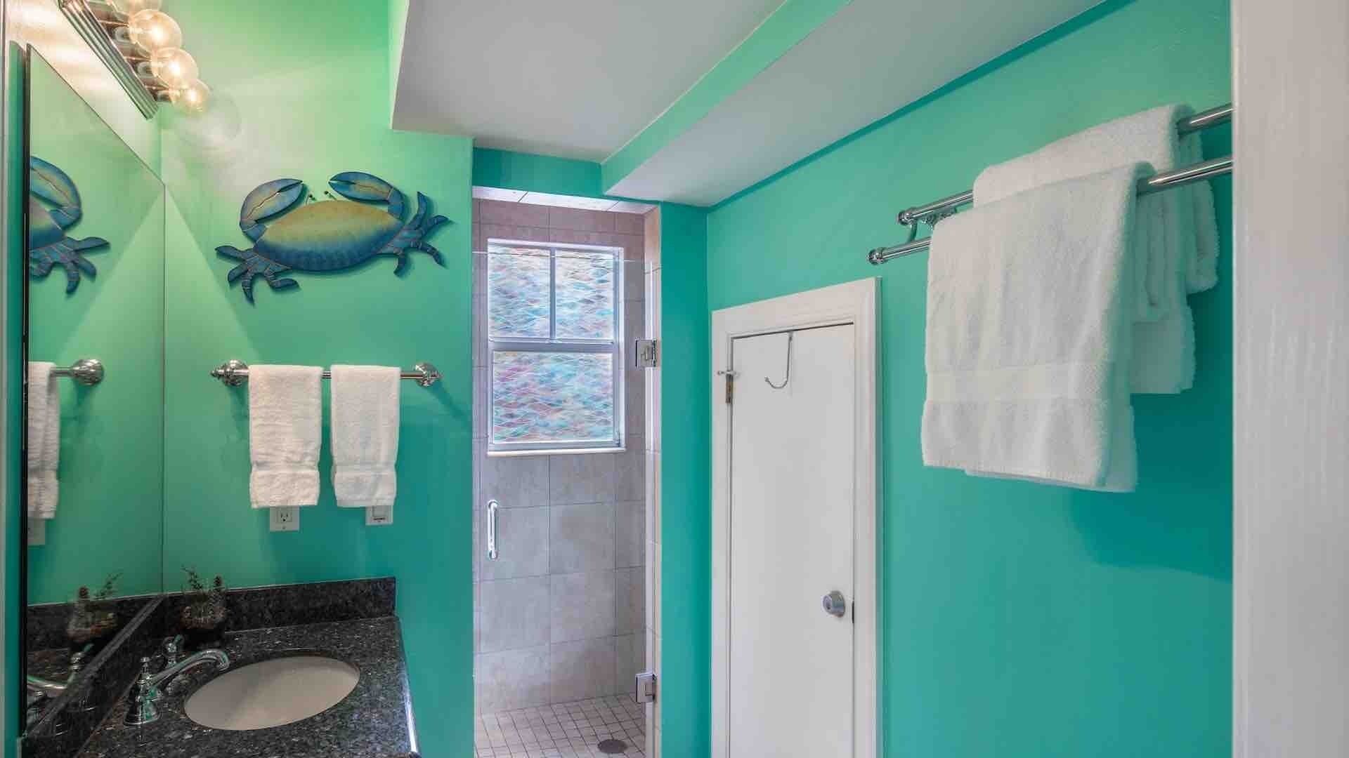 A bathroom with teal walls, a white door, and a sink with a mirror.