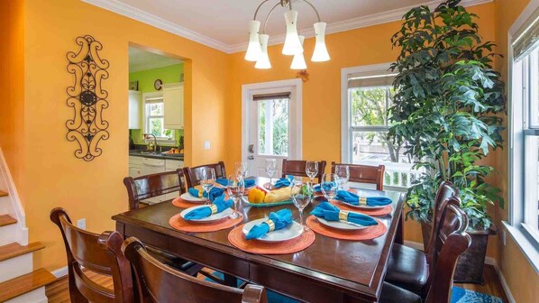 A dining room with a wooden table set for six, surrounded by chairs.