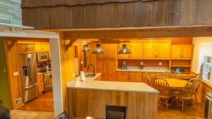 A kitchen with wooden cabinets, stainless steel appliances, and a central island with chairs.