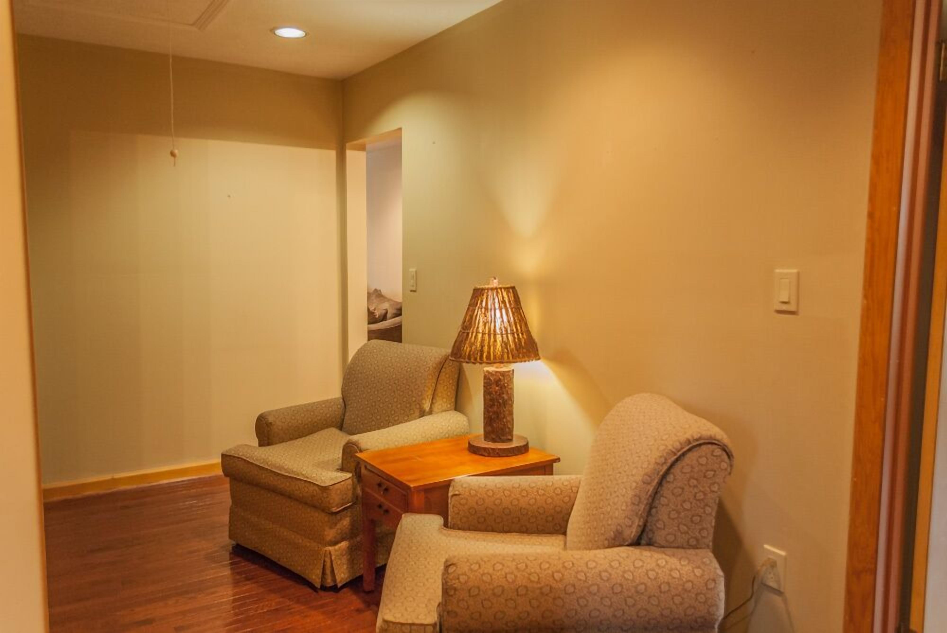 A cozy living room with a sofa, armchair, and a lamp on a wooden table.