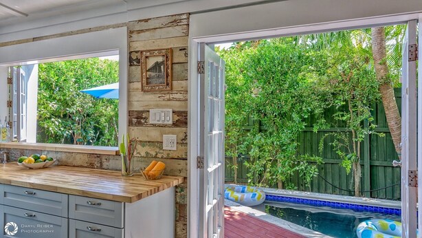 Una cocina con una pared de madera, una ventana con vista a un jardín exuberante y un área de piscina con un flotador.