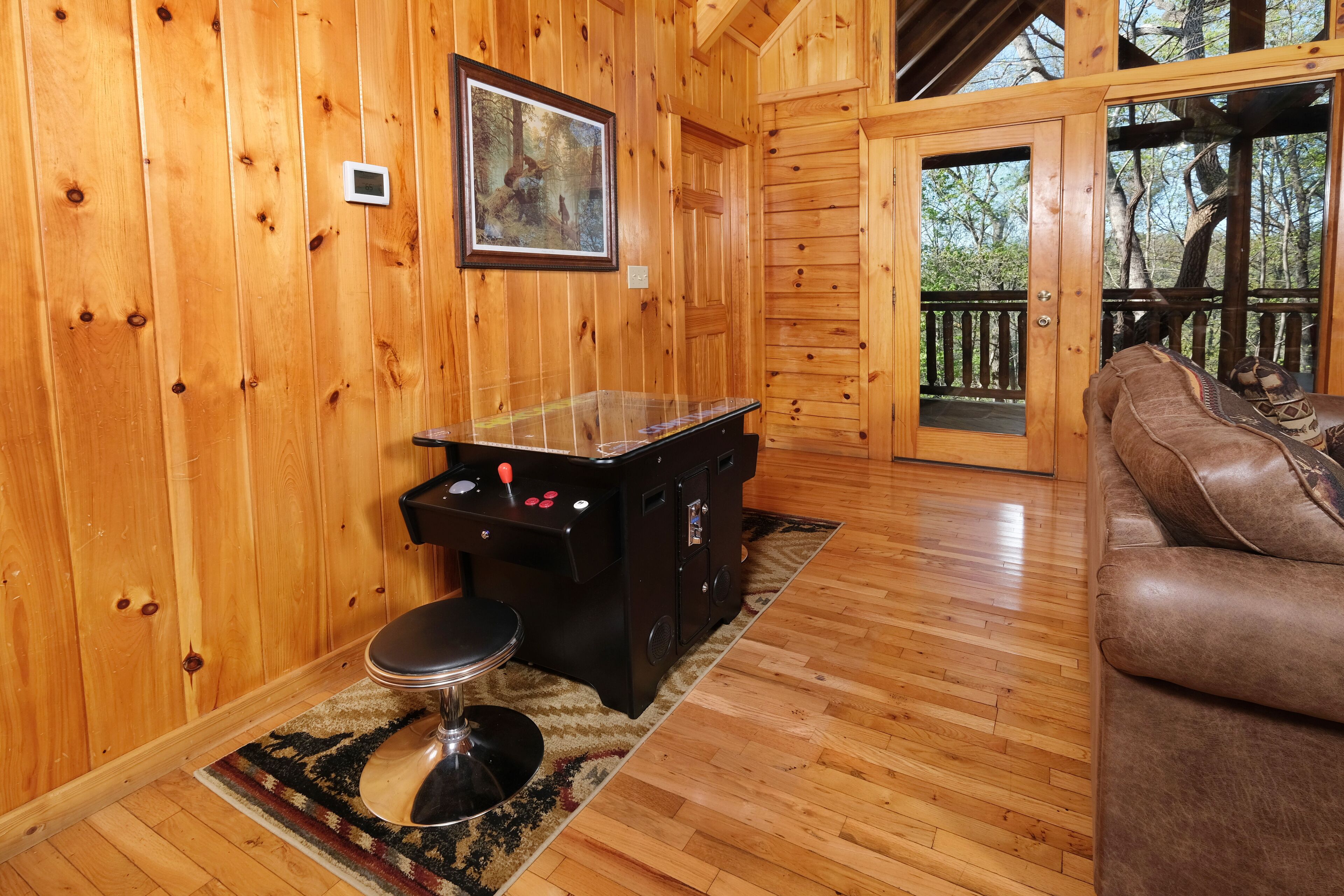 A wooden cabin interior with a pool table, a sofa, and a framed picture on the wall.
