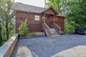 A wooden cabin with a porch, a staircase, and a gravel driveway. - 3 king bedroomss- arcade game, hot tub, & free tickets! (Pigeon Forge)