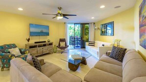 A living room with a sofa set, a coffee table, a TV, and a ceiling fan. - **NATURES EDGE** Ocean Condo / Pool & Tennis + Last Key White Glove Service... (Key West)