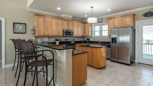 A spacious kitchen with wooden cabinets, a stainless steel refrigerator, and a central island.